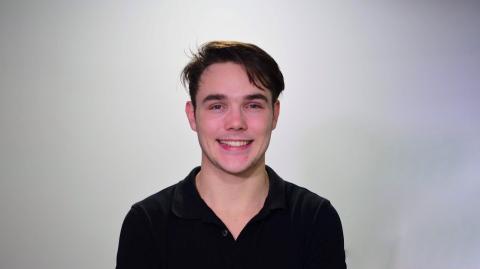 A young man in a black shirt smiling at the camera